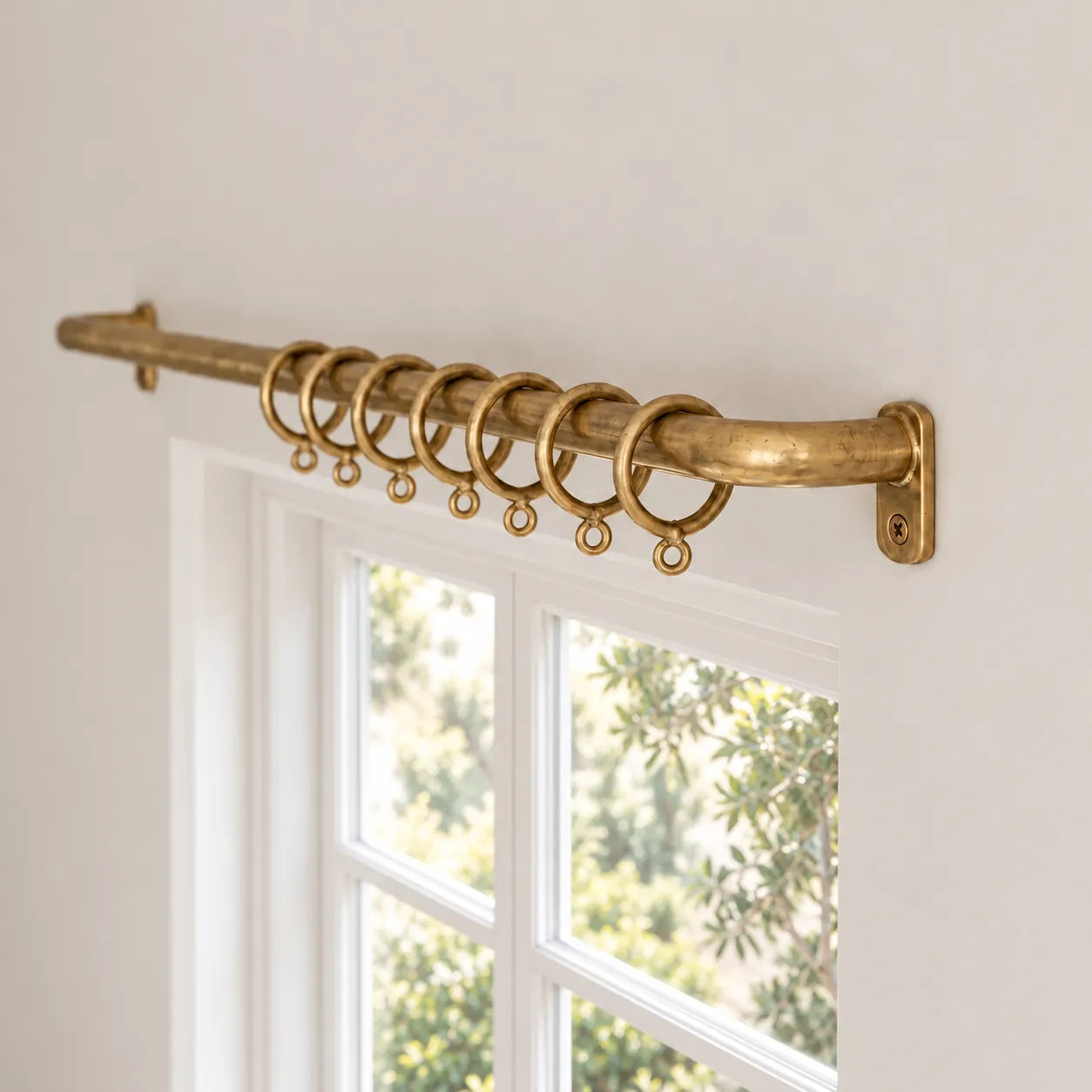 Unlacquered brass French return curtain rod with rings installed above window