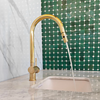 Unlacquered brass pull-down kitchen faucet installed at sink, bright finish