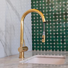 Unlacquered brass pull-down kitchen faucet installed at sink, bright finish