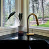 Unlacquered brass pull-down kitchen faucet installed at sink, bright finish