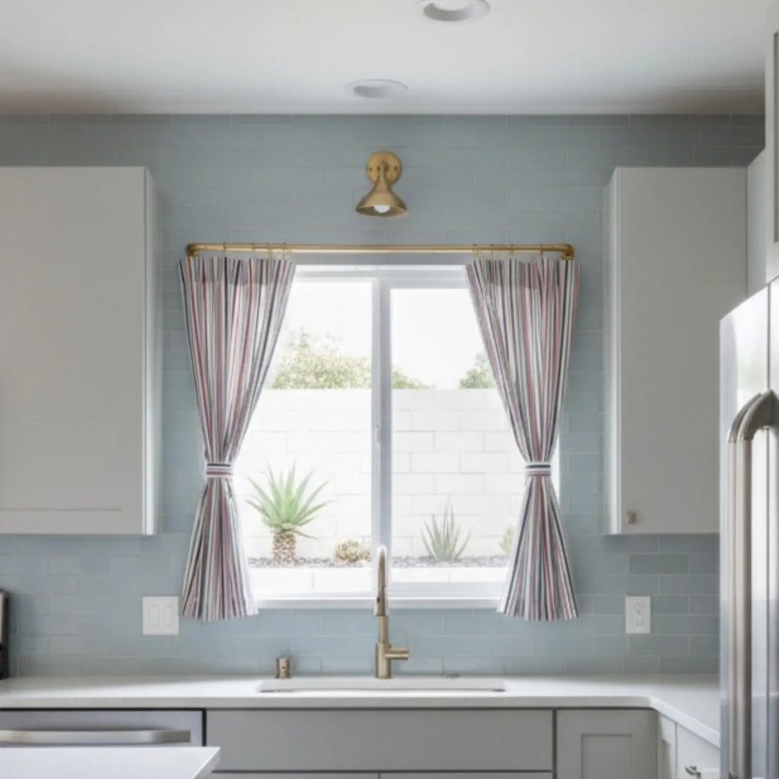 Unlacquered brass French return curtain rod installed above kitchen window