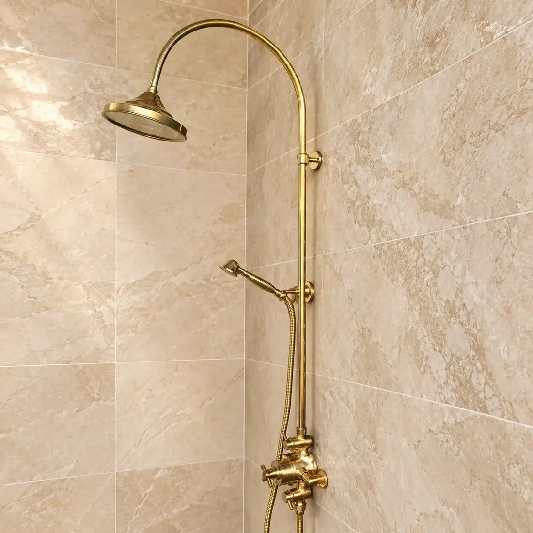 Unlacquered brass exposed thermostatic shower system with handheld shower installed on green and beige tiled bathroom wall