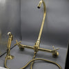 Unlacquered brass wall mount kitchen faucet with sprayer, 8 inch spread
